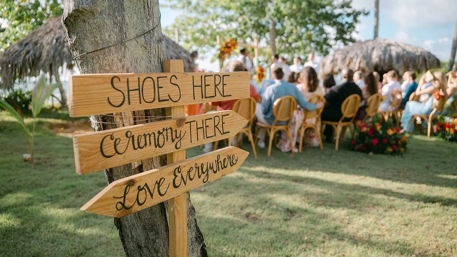 Hand-painted wooden wedding signs at an outdoor ceremony